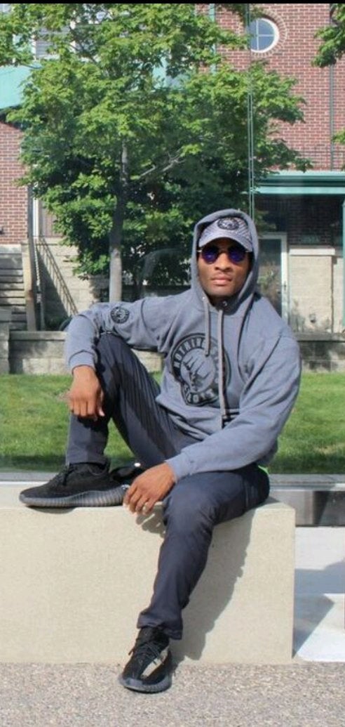 Man sitting on bench wearing Nothing Stops Detroit Unisex Gray with Black Logo One Color Logo Hoodie